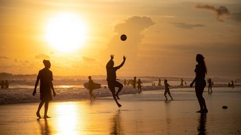 Leute, die am Strand im Sonnenuntergang Vollyball spielen